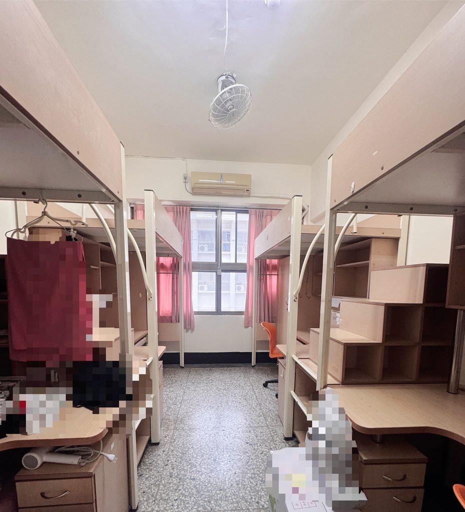 台湾の大学の寮の4人部屋。両側にベッドと机が並び、奥に窓とエアコンがある